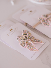 Load image into Gallery viewer, Floral hair bow on a LIVY & LOU branded card with a blurred background