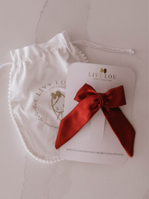 Load image into Gallery viewer, Red satin ribbon on a LIVY LOU branded card with a matching drawstring bag.
