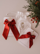 Load image into Gallery viewer, Red satin bow with LIVY LOU branded items on a neutral background
