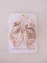 Load image into Gallery viewer, Floral bow hair accessory on a LIVY LOU branded card with a marble background
